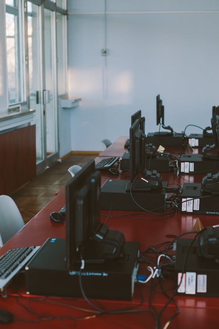 Interior of a computer lab with desktops on a conference table, featuring natural light.